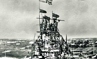 Supervisors, engineers and workers appear quite comfortably perched on wooden scaffolding unfurling the Union Jack