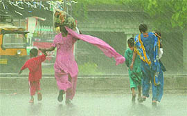 Caught in sudden burst of rain, women along with kids run for cover near Jalandhar on Sunday.