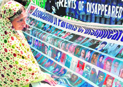 A relative of a disappeared Kashmiri Muslim looks at the photographs of disappeared youth in Srinagar.