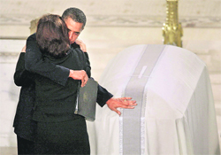 President Barack Obama lays his hand on the casket containing the body of Sen Edward Kennedy as he hugs Kennedy's widow Victoria Kennedy after giving the eulogy at the funeral mass in Boston. 