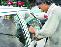 A parking lot attendant opens a door lock of a Maruti car with a measuring scale in Sector 17 in Chandigarh on Monday. 