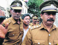 Journalist JS Tissanayagam (C) is escorted by prison officials out of the Colombo High Court on Monday.