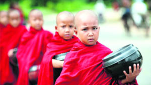 Buddhist monks walk down a road collecting alms in Pyi town of Burma on Monday.