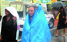 Tourists protect themselves from rain with polythene sheets near the Golden Temple in Amritsar.