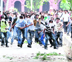 College students stone policemen during a protest over the varsity issue in Jammu on Tuesday. 