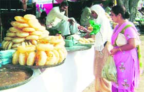 Women buy khajla, a traditional sweetmeat, at the mela site