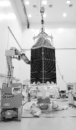 Workers checking the Kepler spacecraft as it is lifted for weighing at the Hazardous Processing Facility at Astrotech in Titusville, Florida.