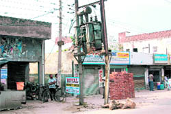 A rickety pole supports a transformer in a densely-populated area of Sahnewal.