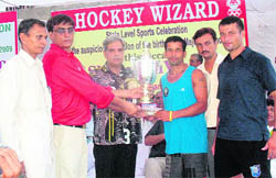 Paramvir Rathi, president, Haryana Olympic Association, gives away the trophy to the Sonepat team captain.
