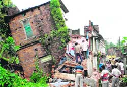 Residents gather as a house collapsed due to heavy rain at Kulti in Bardhaman district of West Bengal on Monday. Two persons were killed in the mishap.