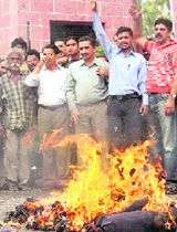 BJP activists burn an effigy of the central government at the Clock Tower in Dehradun on Tuesday.