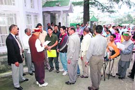 Prof Prem Kumar Dhumal, wearing a typical Himachali cap and in sports shoes, listening to grievances of the people at Shimla