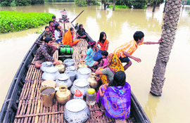 Villagers transport drinking water on a boat during a flood in Ghatal, some 95 km south of Kolkata,on Wednesday. Four persons, including two children, were killed in West Bengal by widespread rainsand release from a Damodar Valley Corporation reservoir which led to a flood-like situation in fivedistricts of the state. 