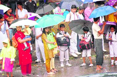 Students and parents wait for a bus at a stop in Dehradun