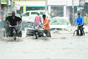 People wade through water in a low-lying area in Karnal on Thursday.