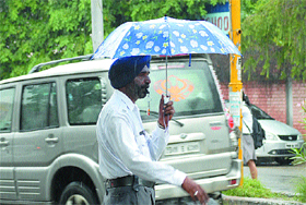 A traffic policeman performs his duty outside the APJ campus carrying an umbrella on a rainy day in Jalandhar on Friday.