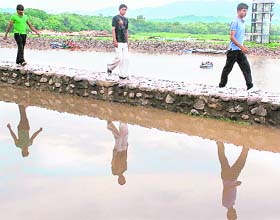 MIRROR IMAGE: Youngsters walk on the pavement as the road at the Sukhna Lake is waterlogged following heavy rains during the past few days