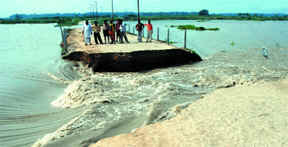 People witness the water flow after a dam collapsed at Tisra Pusta, Usmanpur near Majnu ka Tilla in New Delhi on Sunday.