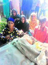 Family members and kin sit beside the body of Noor Hussain.
