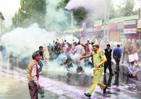State Road Transport Corporation employees run for refuge as the police makes use of teargas shells and water cannons during a protest in Srinagar