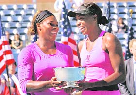 Serena (L) and Venus Williams with the doubles trophy in New York