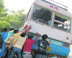 Agitated students try to overturn a bus near the bus stand at Panchkula on Wednesday.