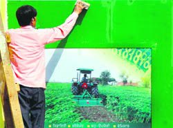  A worker gives final touches to a hoarding for the two-day kisan mela beginning at the PAU, Ludhiana, from Thursday.