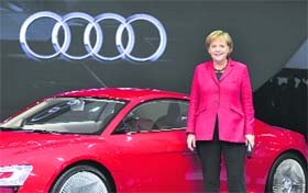 German Chancellor Angela Merkel poses for the media in front of an Audi e-tronic concept sports car at the booth of German car manufacturer Audi during the 63rd international car show IAA in Frankfurt