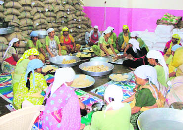 Women from economically weaker sections make puris for a Monday special under the mid-day meal project