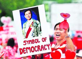 A supporter of exiled former Thailand premier Thaksin Shinawatra holds a poster with his portrait during a rally at the Royal Plaza in Bangkok
