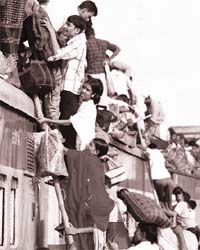 Passengers climb aboard an overcrowded train at a railway station in Dhaka