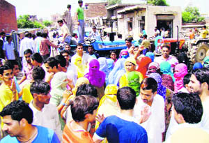 Residents of Dairy Mohalla resort to road blockade to press for their demand for construction of a cemented street in Rohtak on Monday.
