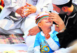 A man adjusts the cap of his son on the occasion of Eid-ul-Fitr at Jama Masjid in Ludhiana on Monday.