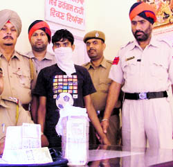 The accused in police custody along with the stolen money in Ludhiana on Monday.