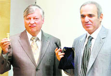 Former chess world champions Garry Kasparov (R) and Anatoly Karpov pose with their chess figures at a news conference in Valencia on Tuesday before their 25th anniversary match to be held from Tuesday to Thursday.
