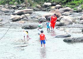 A family crosses a rivulet following heavy rains on Saturday morning at Gazalwadi village on the outskirts of Dehradun