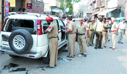 Policemen inspect a vehicle damaged in a firing incident in Jalandhar