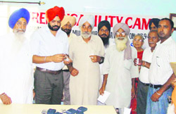 Manpreet Singh Ayali, chairman of Zila Parishad, and others hand over hearing aid to a needy person at the camp organised in Mullanpur Dakha 