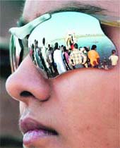 A devotees glasses reflect the immersion of an idol of Goddess Durga into the Yamuna on Vijay Dashmi in New Delhi on Monday