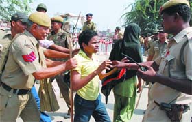 Police personnel catches a boy who was part of the mob that protested on Wazirabad Road over the Khajoori Khas school stampede