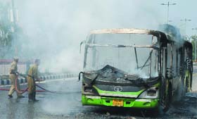 Delhi fire personnel douse flames of the DTC bus that was torched by the mob