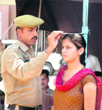 A policeman measures the height of a girl who took part in the recruitment rally in Jammu on Tuesday.