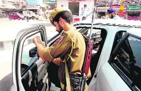 A policeman removes dark film from the windowpane of a car at Indira Chowk in Jammu