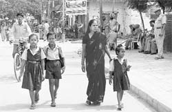 A mother accompanies her children to a school in New Indira Colony in Manimajra on Thursday.