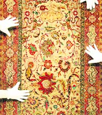 Sothebys auction house employees pose with a late 16th-early 17th century Safavid silk, wool and metal-thread prayer rug in London