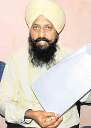 Harbans Singh shows documents at a press conference in Sector 35, Chandigarh, on Saturday.