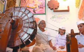 Schoolchildren try their hands on the spinning wheel at Gandhi Jayanti Mela in New Delhi on Saturday. 