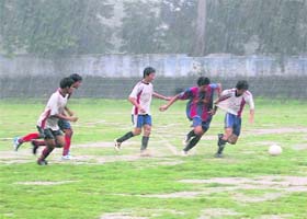 Players vie for the ball in a rain-soaked match of the District Football League in Dehradun