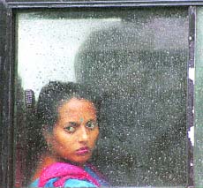 A woman looks through the window of a local bus as rain lashed Jammu on Sunday.