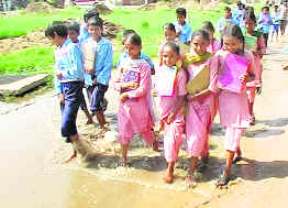 Schoolchildren wade through a waterlogged road at Leela Megh Singh village, near Jagraon. 